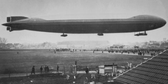 Crowds gather to watch the Zeppelin L43 land on a field